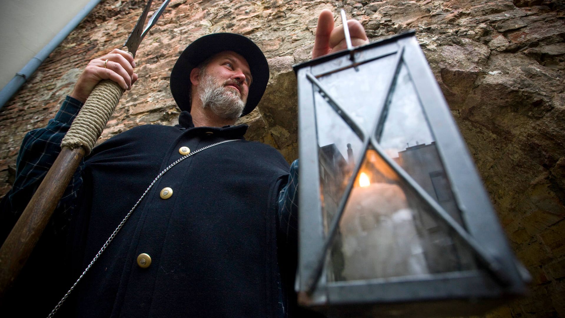 Stadtführer im historischen Gewand hält eine Laterne