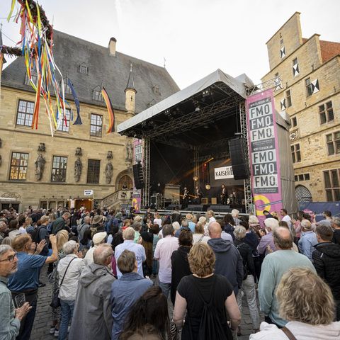 Vor der Kulisse des historischen Rathauses feiern Menschen vor einer der Maiwochen-Bühnen