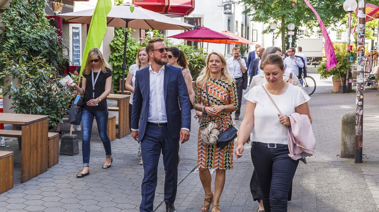 Eine Gruppe von Personen läuft entspannt durch die Straßen Osnabrücks. Im Rahmen einer Tagen erkunden Sie bei bestem Wetter die Stadt.